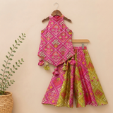 Vibrant pink and green silk two-piece set featuring a printed halter top with playful tassels and a flowy palazzo