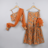 Rust Orange Paisley Printed One-Shoulder Sharara Set with Organza Cape Sleeves and Matching Potli Bag.