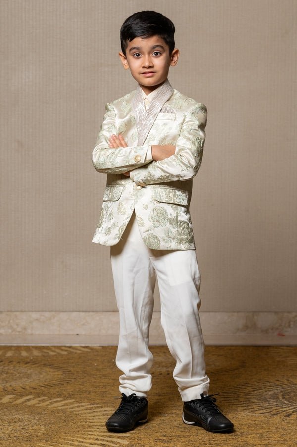 Elegant brocade suit jacket with floral patterns paired with crisp white trousers and a classic ivory shirt for a regal and sophisticated look. - Kirti Agarwal