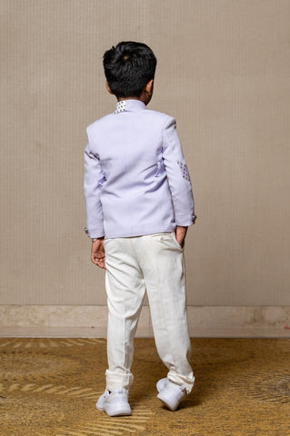 Trendy lavender blazer with metallic stud embellishments paired with classic white trousers, perfect for the modern young gentleman. - Kirti Agarwal