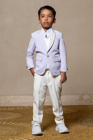 Trendy lavender blazer with metallic stud embellishments paired with classic white trousers, perfect for the modern young gentleman. - Kirti Agarwal