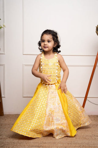 Vibrant yellow sleeveless dress with playful prints and tassel accents, perfect for festive celebrations and joyful occasions. - Kirti Agarwal